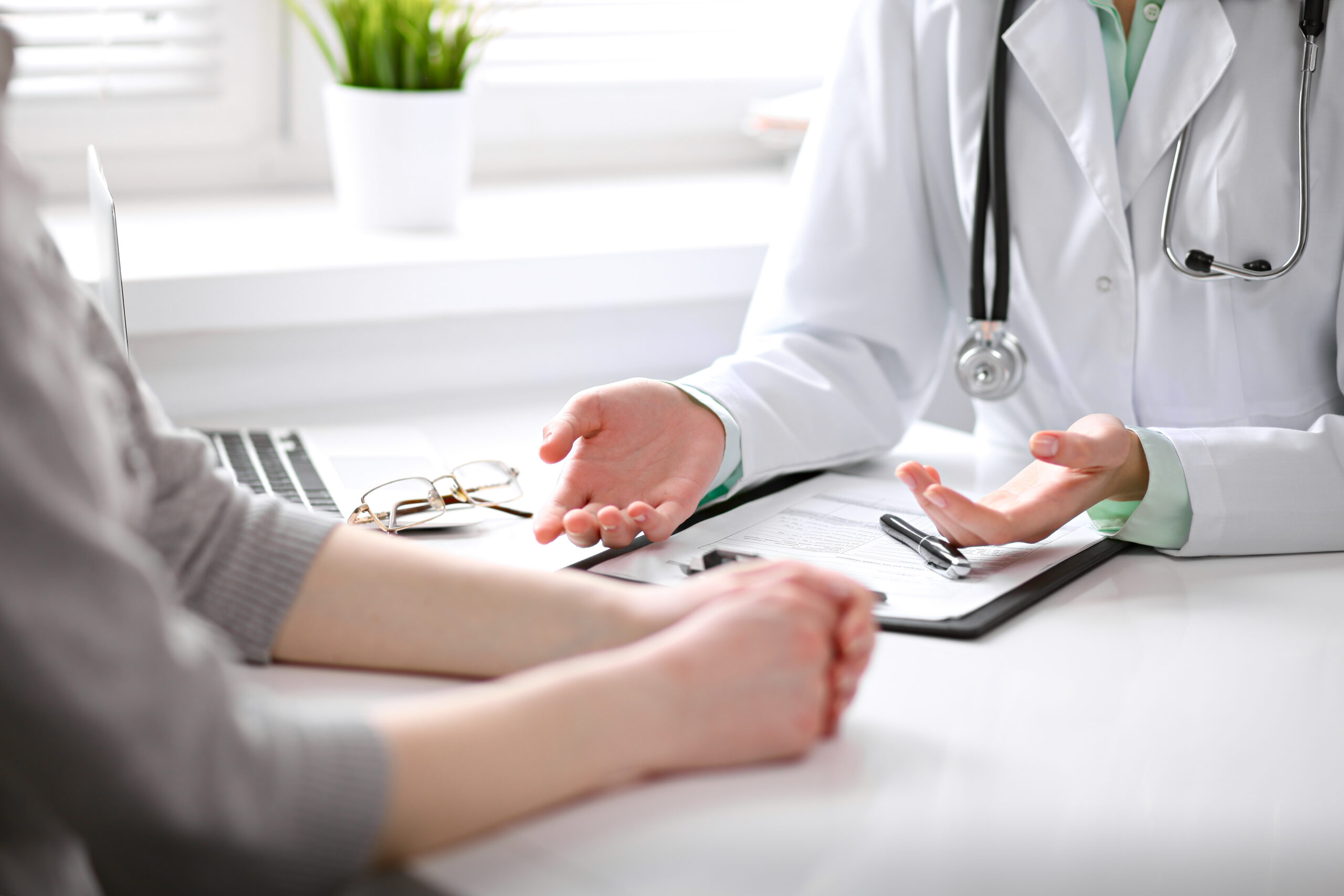Close Up Of Doctor And Patient Sitting At The Desk